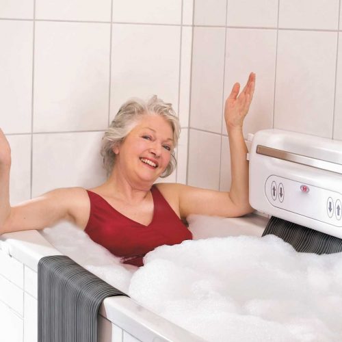 Seniorin in Hamburg nutzt Badewannenlift mit Fernbedienung